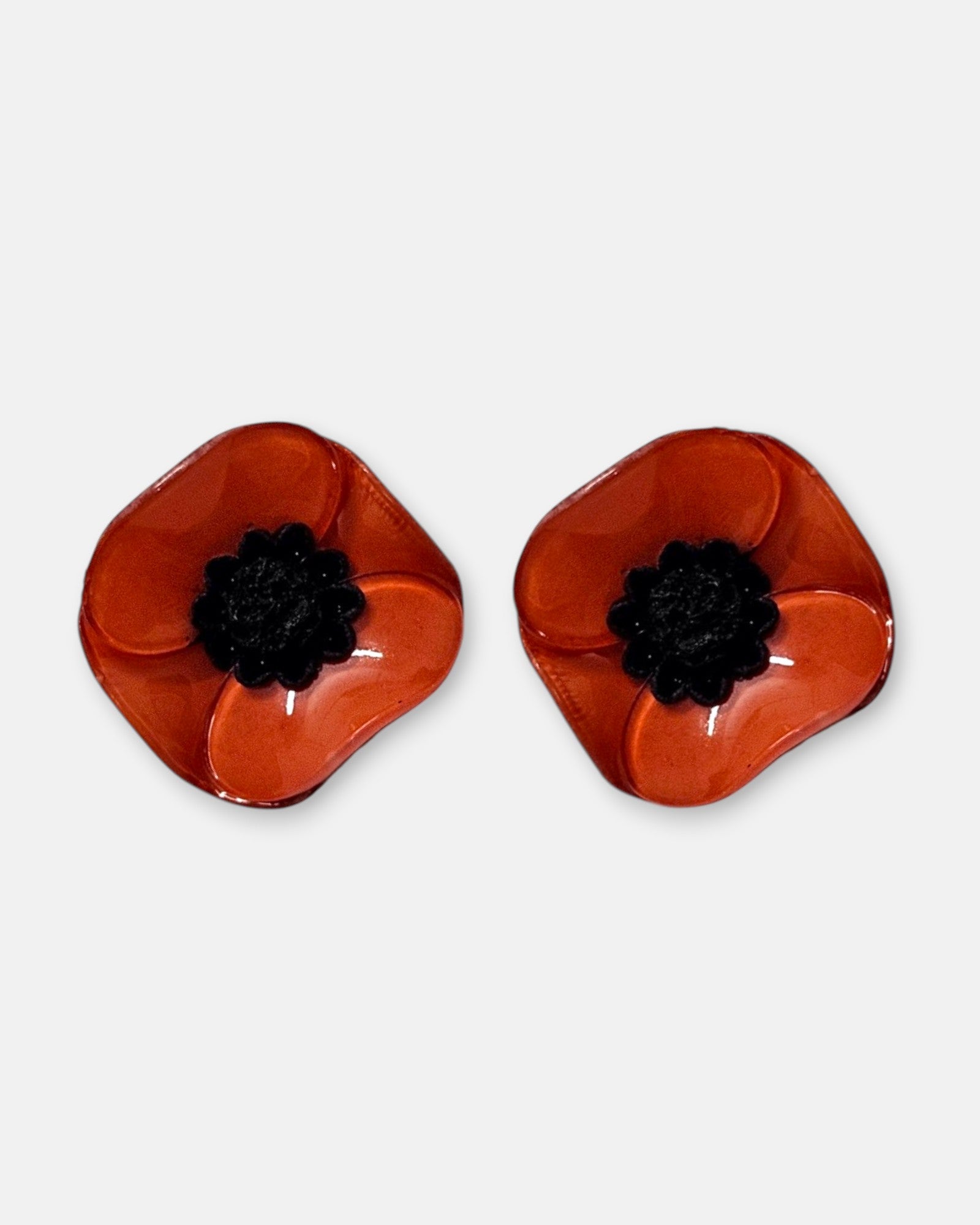 par de pendientes pequeños de presión con forma de flor de amapola de Ciléa Paris, detallando sus pétalos de resina esmaltada en tono rojo pasión brillante y su centro negro estrellado.