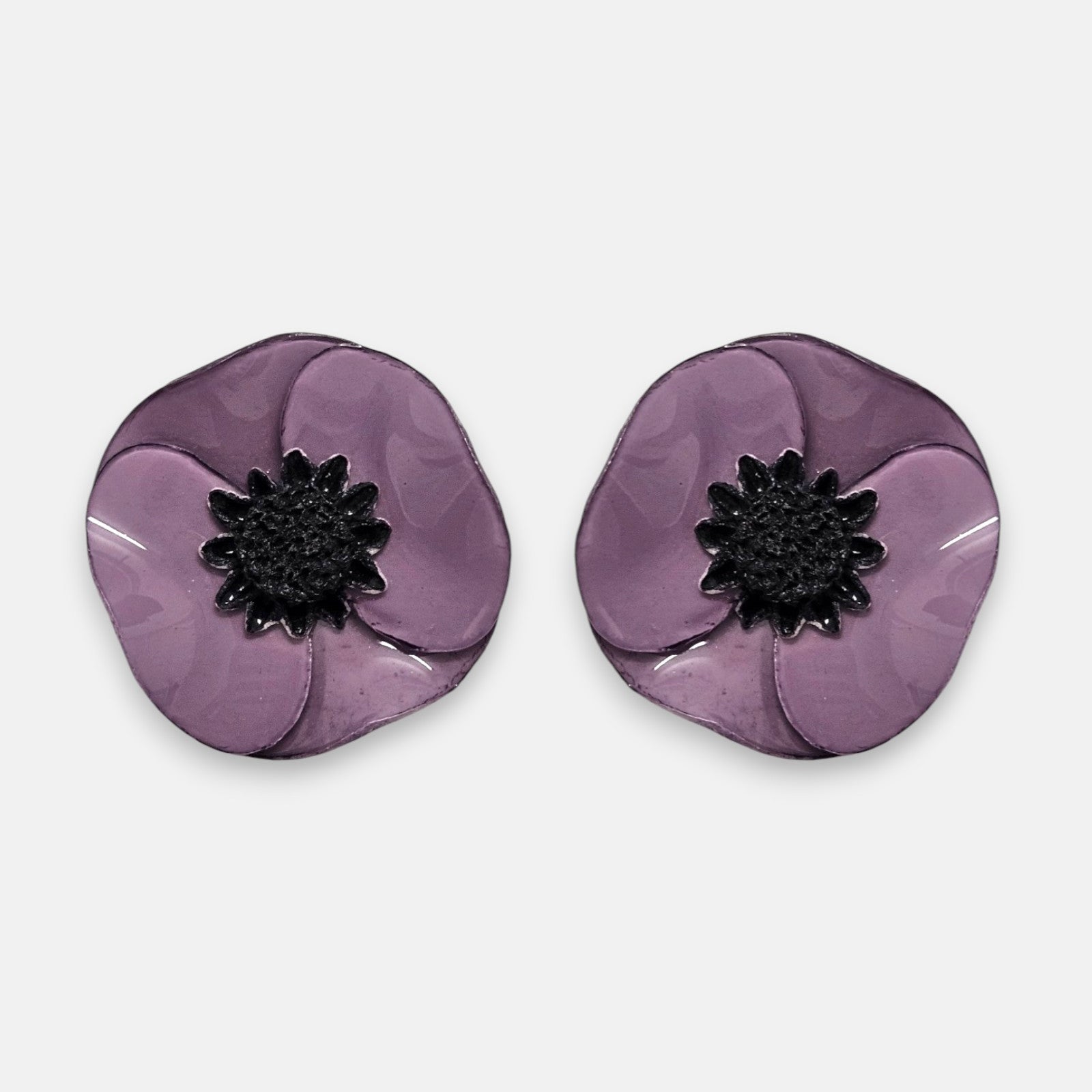 par de pendientes de clip con forma de flor de amapola de Ciléa Paris, detallando sus pétalos de resina esmaltada en tono violeta medio y su centro negro estrellado.