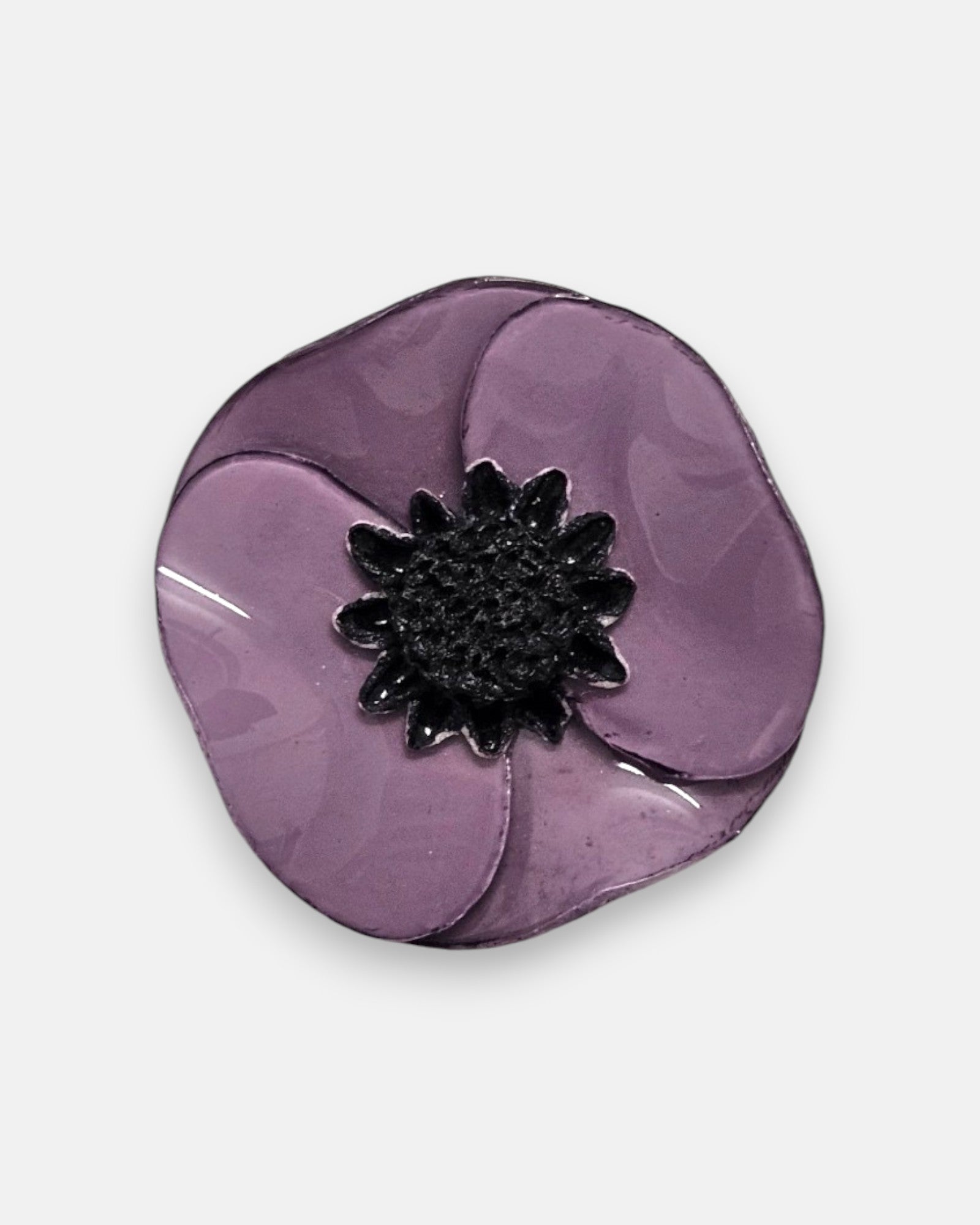 primer plano macro de un pendiente, permitiendo apreciar el brillo esmaltado de la superficie violeta y la textura rugosa del pistilo central oscuro.