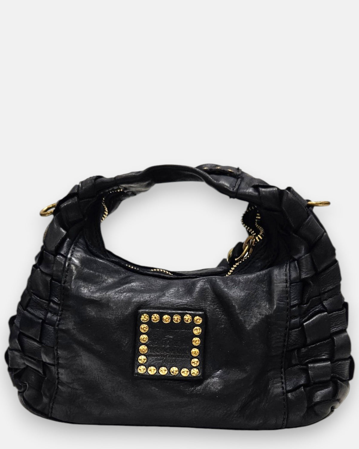 reverso en piel negra lisa del bolso, detallando en el centro el parche cuadrado de piel grabado con el logotipo de Campomaggi y tachuelas doradas envejecidas.