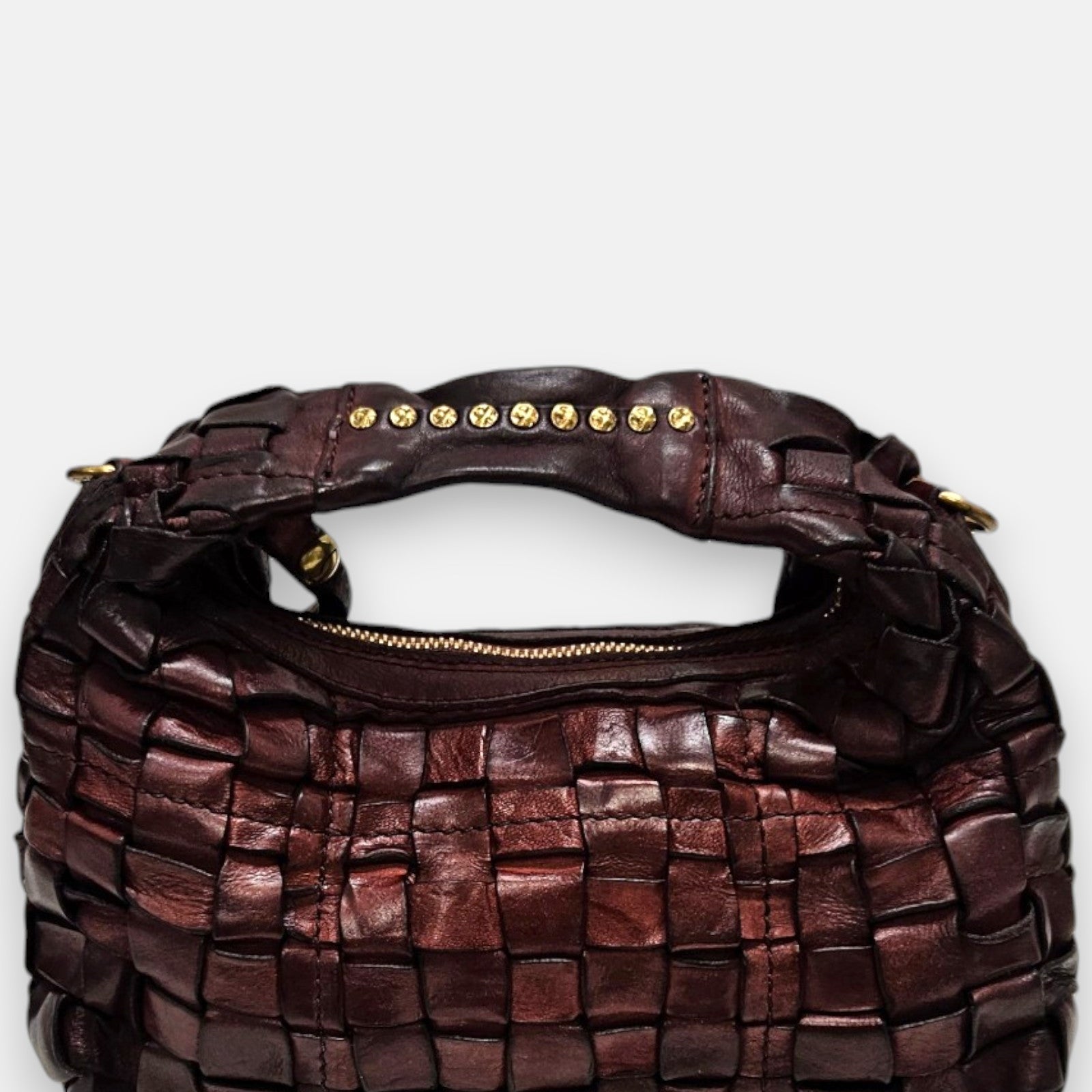 bolso Agnese pequeño de piel elaborada a mano, destacando su textura tridimensional y su asa superior con tachuelas doradas.