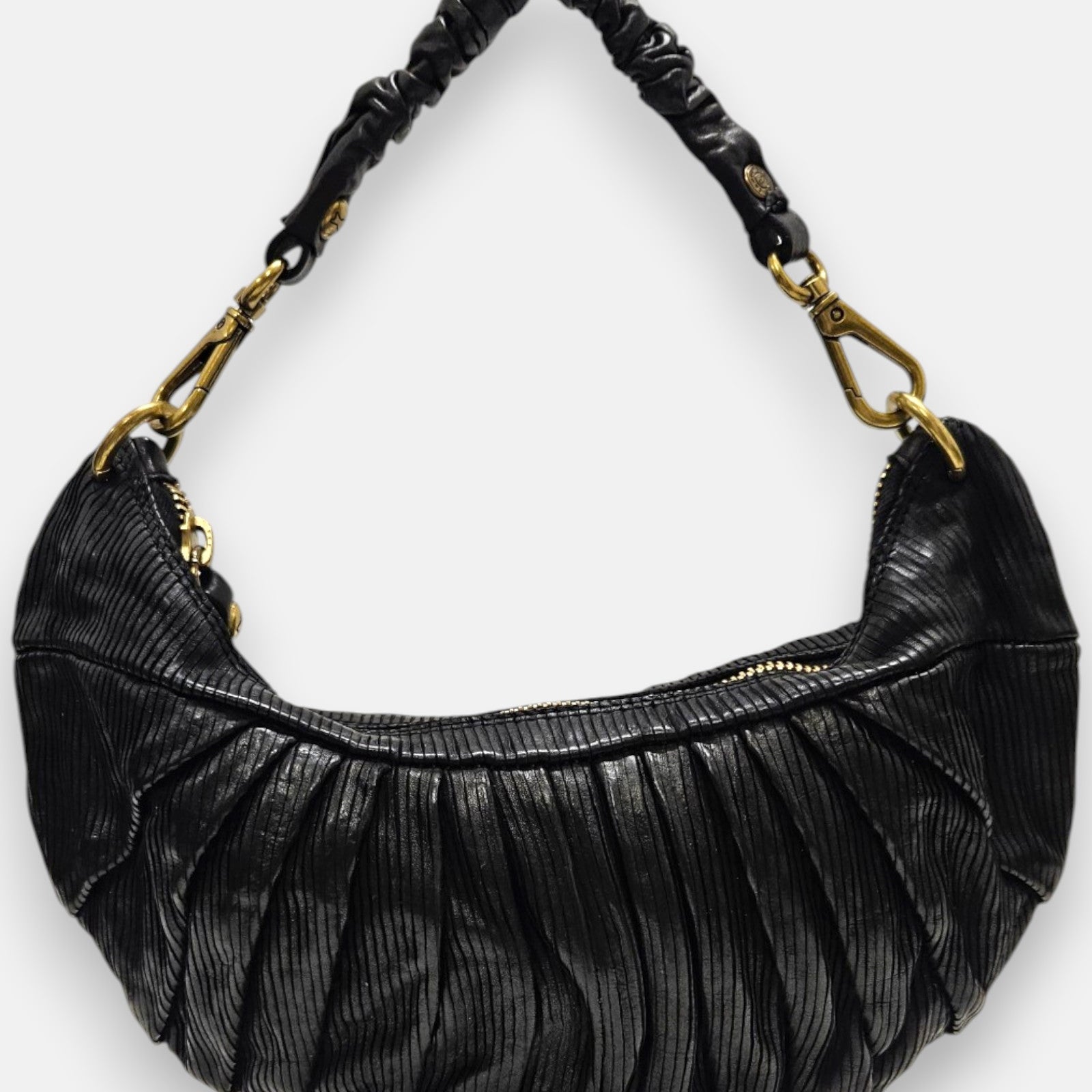 bolso Carlotta de piel negra con plizado vertical, silueta media luna y asa fruncida con mosquetones dorados.