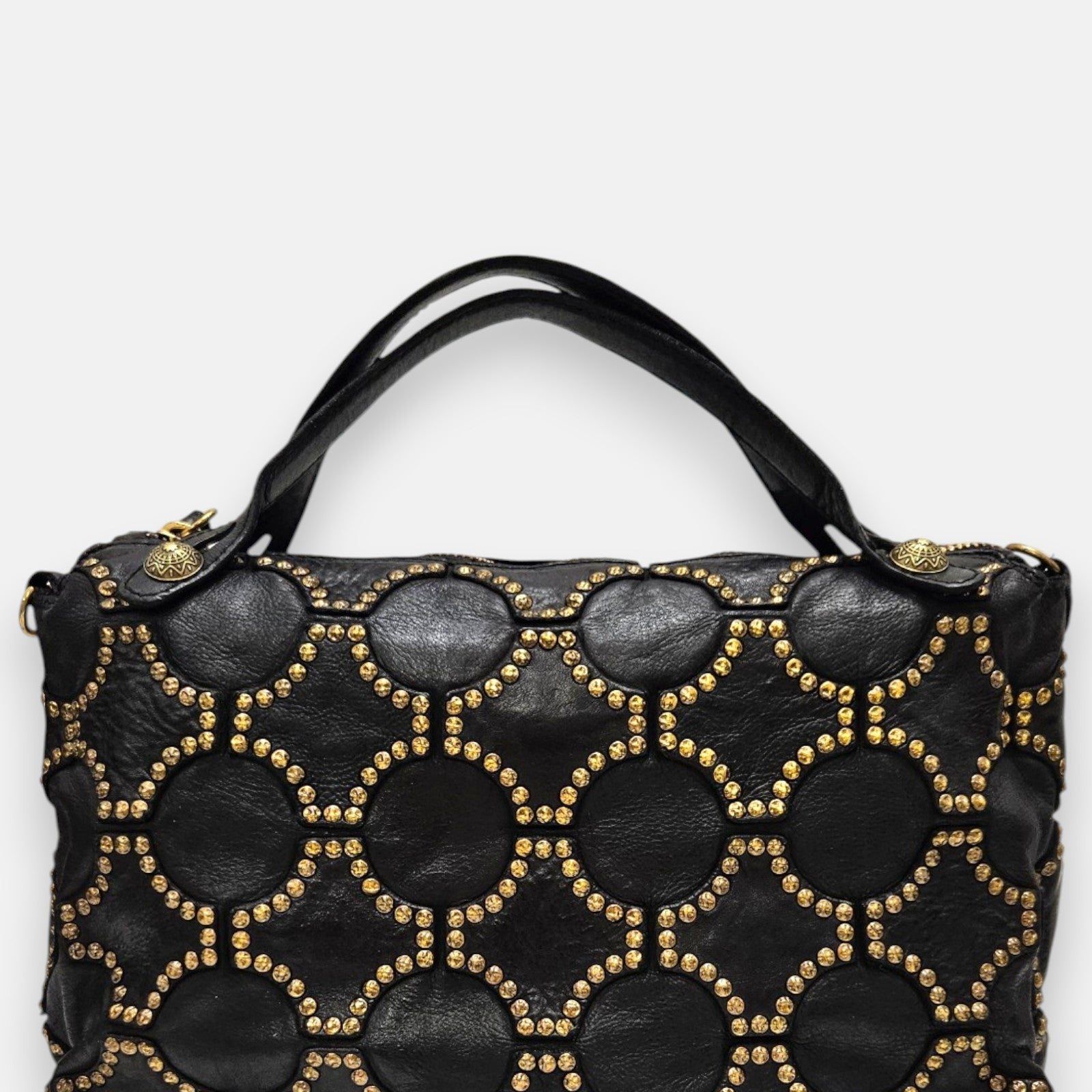 bolso Luciana de piel negra, destacando su elaborado mosaico geométrico de tachuelas doradas y sus dobles asas de hombro.