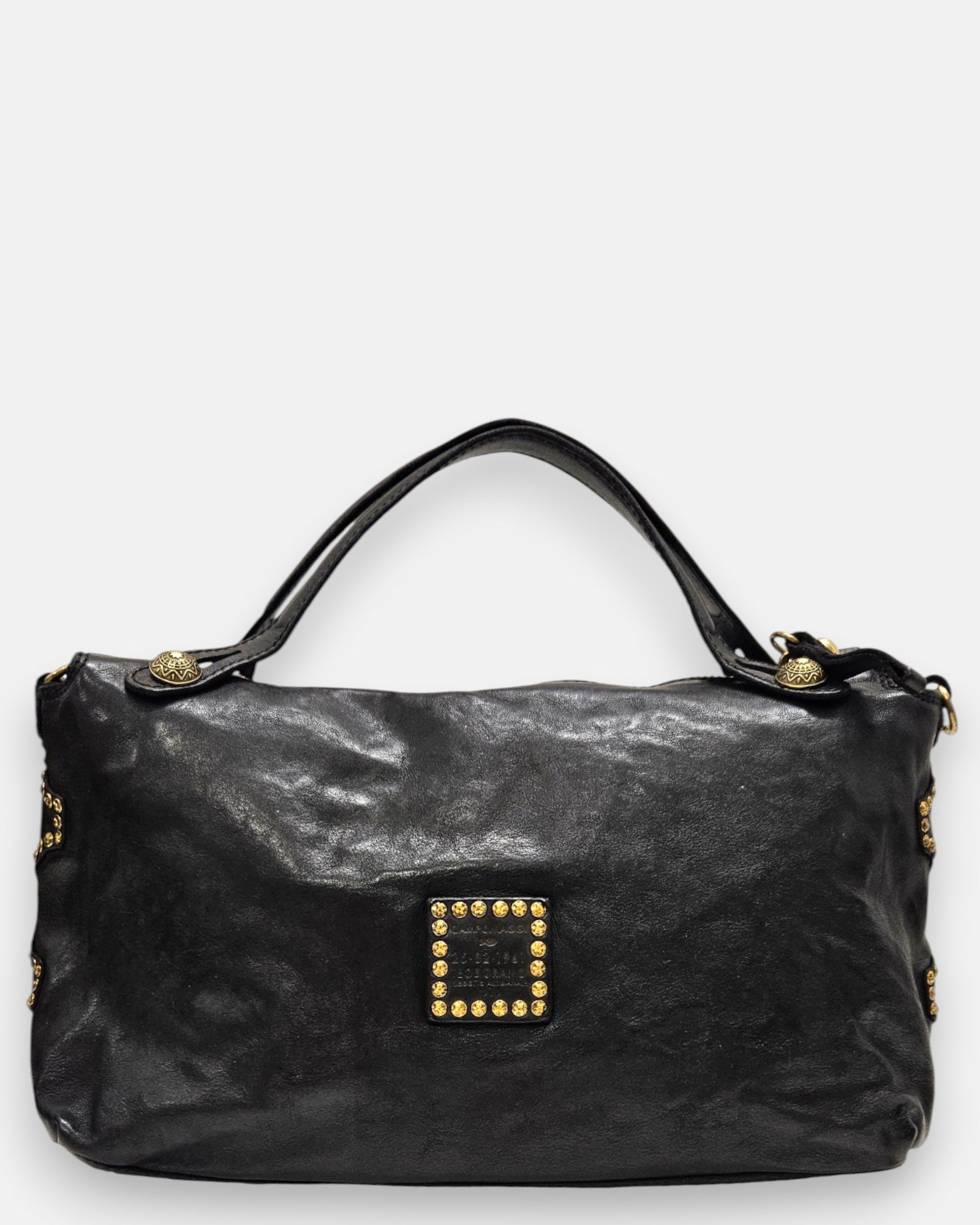 reverso en piel negra lisa del bolso Luciana, detallando en la parte inferior el parche cuadrado de piel con tachuelas doradas envejecidas.