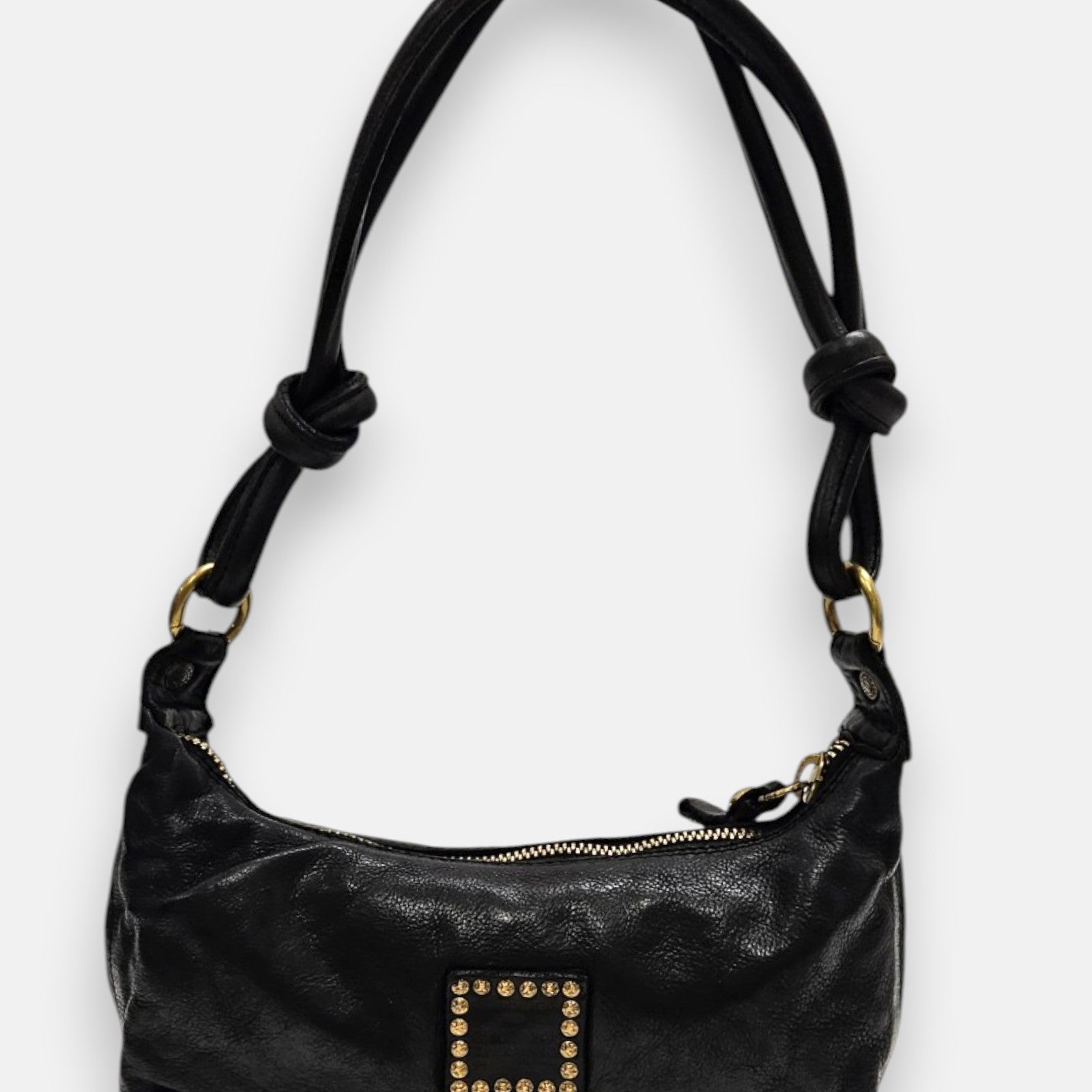 bolso Bianca de piel negra con asas tubulares anudadas y parche central de piel con tachuelas doradas.