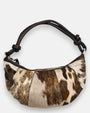 bolso Elena de piel con pelo corto manchado en tonos beige y marrón, silueta media luna y asa anudada.