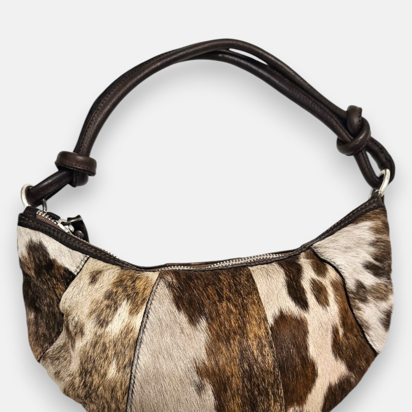 bolso Elena de piel con pelo corto manchado en tonos beige y marrón, silueta media luna y asa anudada.