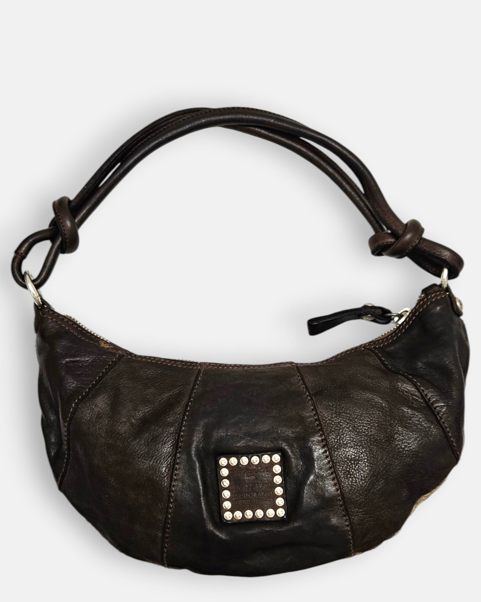 reverso en piel marrón lisa del bolso Elena, detallando en el centro el parche cuadrado de piel con tachuelas plateadas envejecidas.