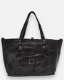 reverso en piel gris lisa del bolso Chiara, detallando en la parte inferior el parche cuadrado de piel con tachuelas plateadas envejecidas.