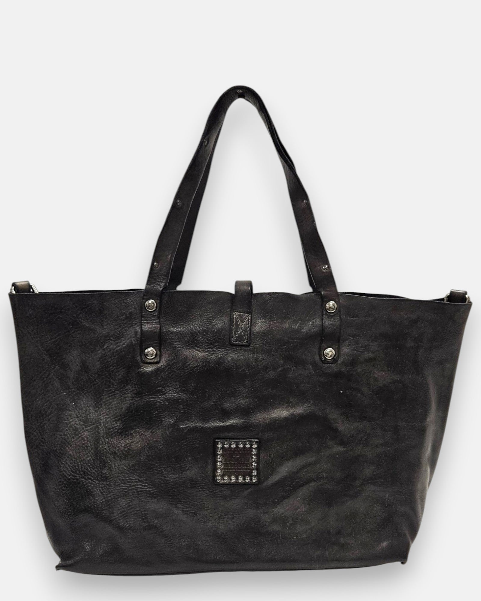 reverso en piel gris lisa del bolso Chiara, detallando en la parte inferior el parche cuadrado de piel con tachuelas plateadas envejecidas.