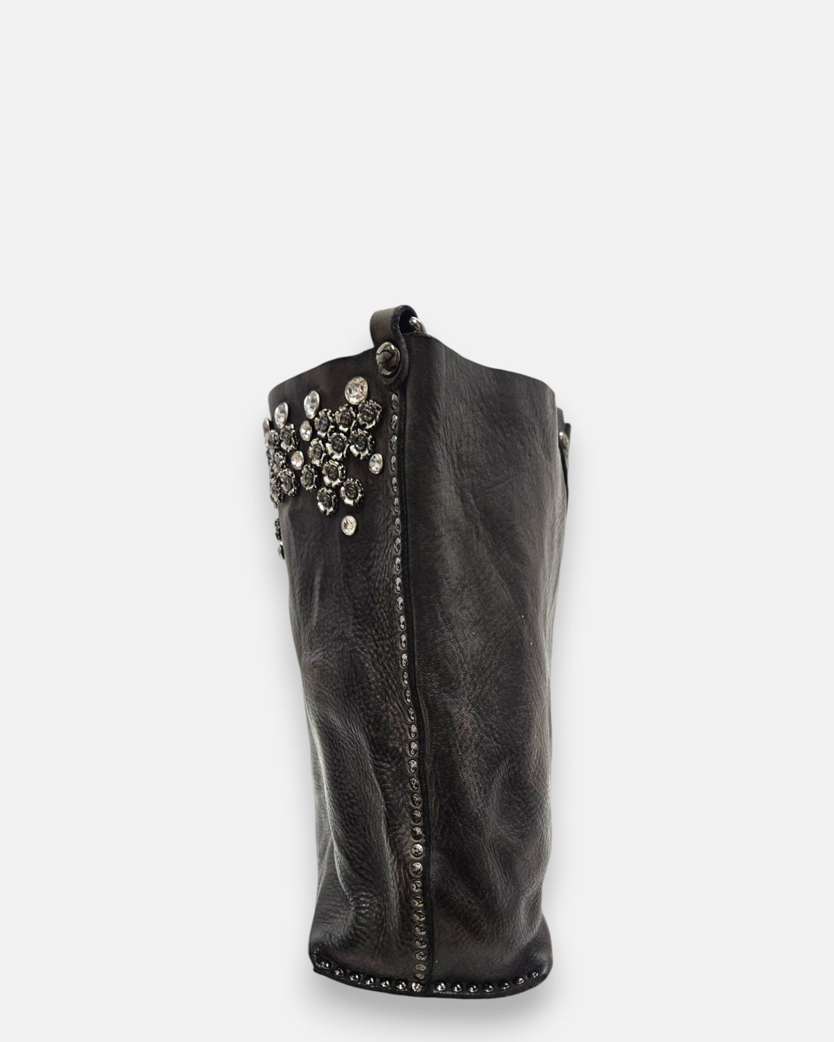 lateral del bolso Chiara, mostrando la amplitud del fuelle y la tira de remaches que bordea las costuras laterales.