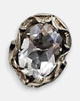 primer plano macro del pendiente Eos, permitiendo apreciar el cincelado artesanal de la montura de plata y el facetado brillante del cristal ovalado.