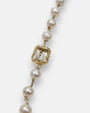 primer plano macro de la pulsera Fiorenza, permitiendo apreciar el cincelado artesanal del engaste chapado en oro, la transparencia del cristal esmeralda y la perla nacarada.