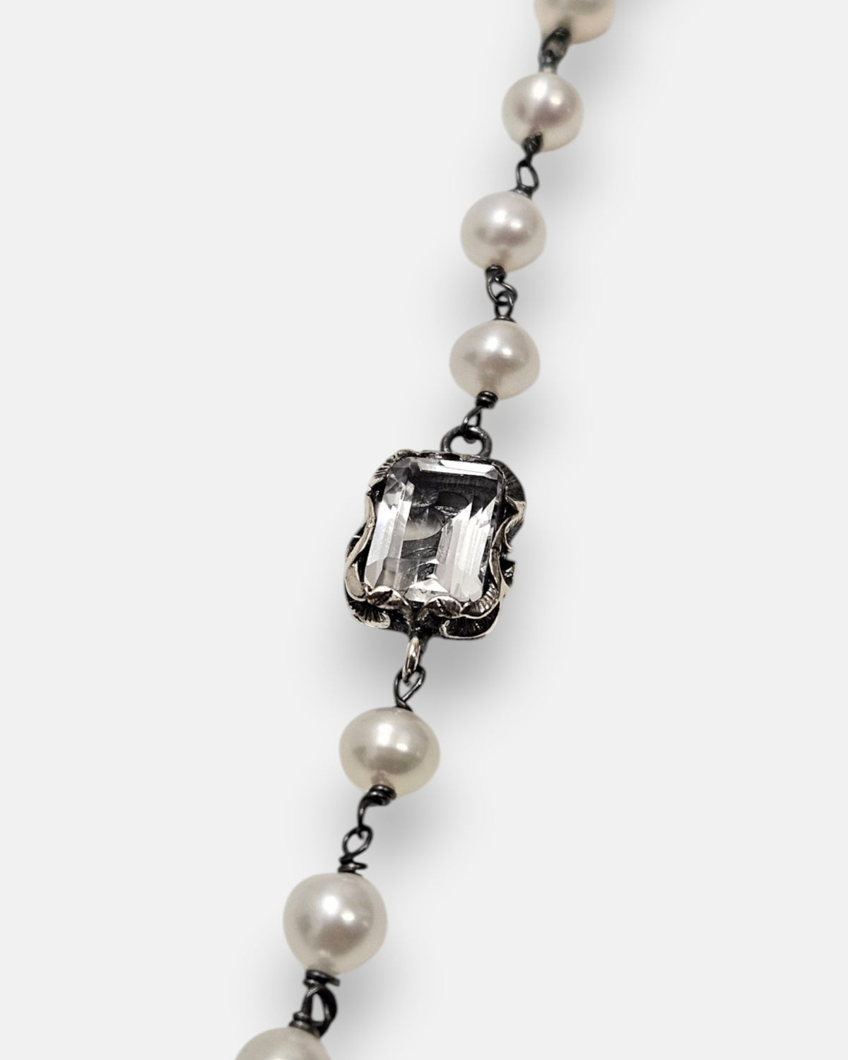 primer plano macro de la pulsera Elettra, permitiendo apreciar el cincelado artesanal del engaste en plata bruñida, la transparencia del cristal esmeralda y el brillo de las perlas.