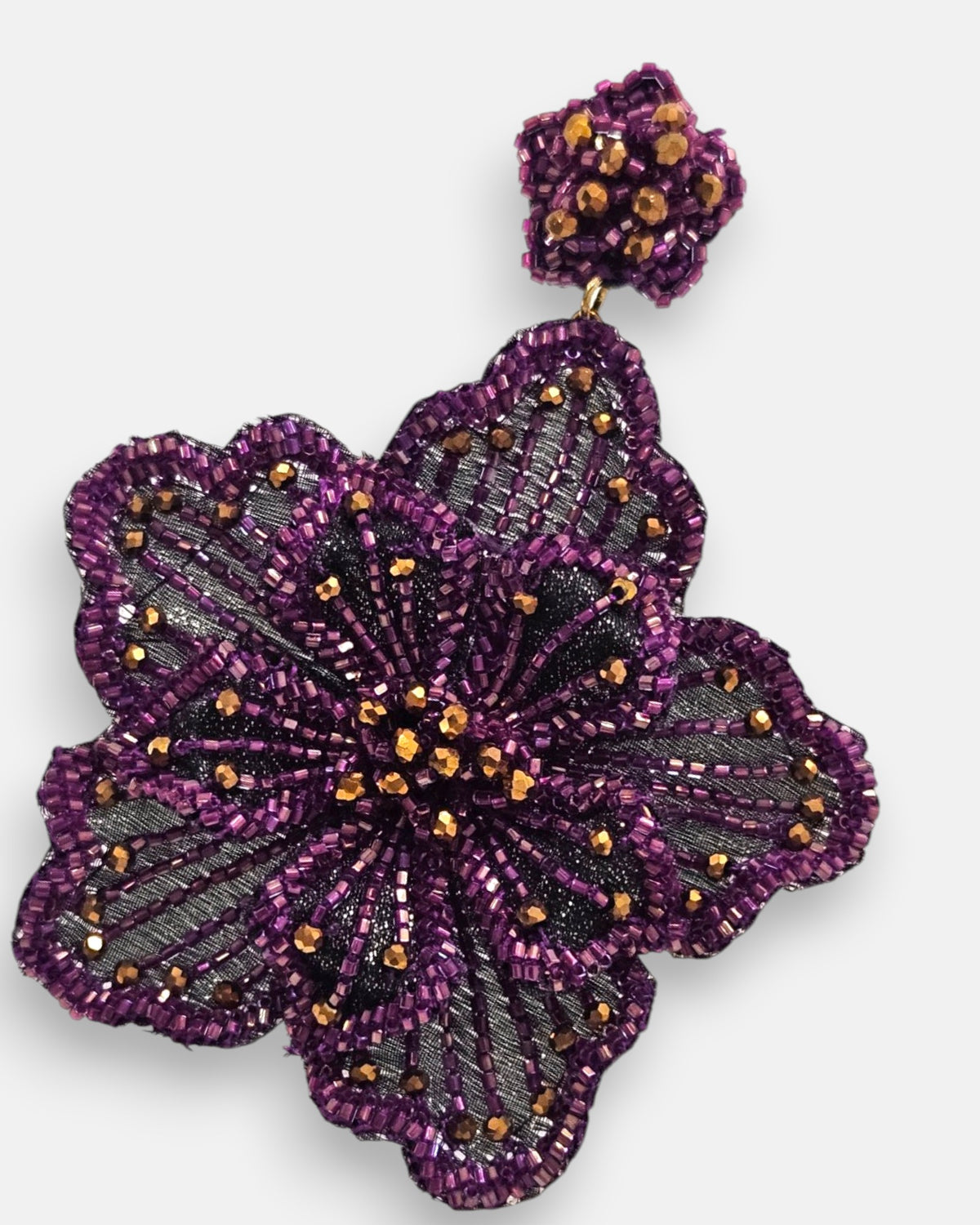 primer plano macro del pendiente Fleur Violette, permitiendo apreciar el trabajo artesanal de bordado sobre tul y los destellos dorados del centro floral.