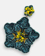 primer plano macro del pendiente Fleur Vert et Jaune, permitiendo apreciar el bordado artesanal en verde iridiscente y el centro de cuentas amarillas.