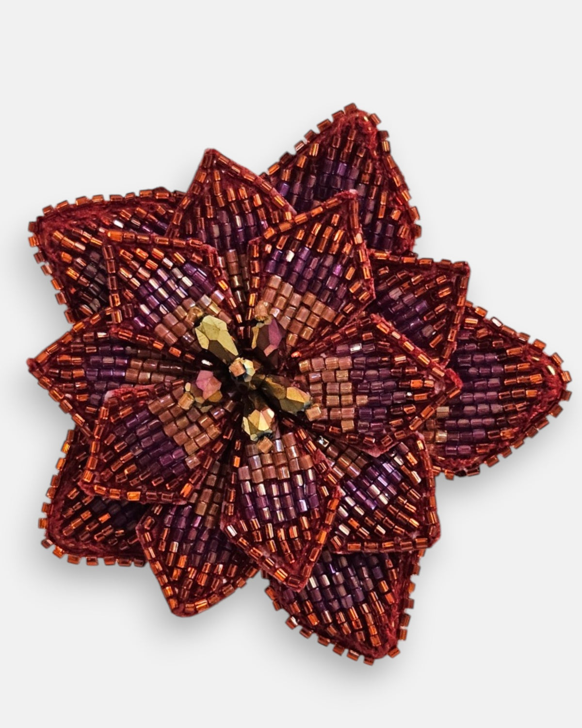 primer plano macro del pendiente Fleur de Lotus Rouge, permitiendo apreciar el trabajo artesanal de las microcuentas en rojo rubí y los destellos del centro de cristales cobrizos.