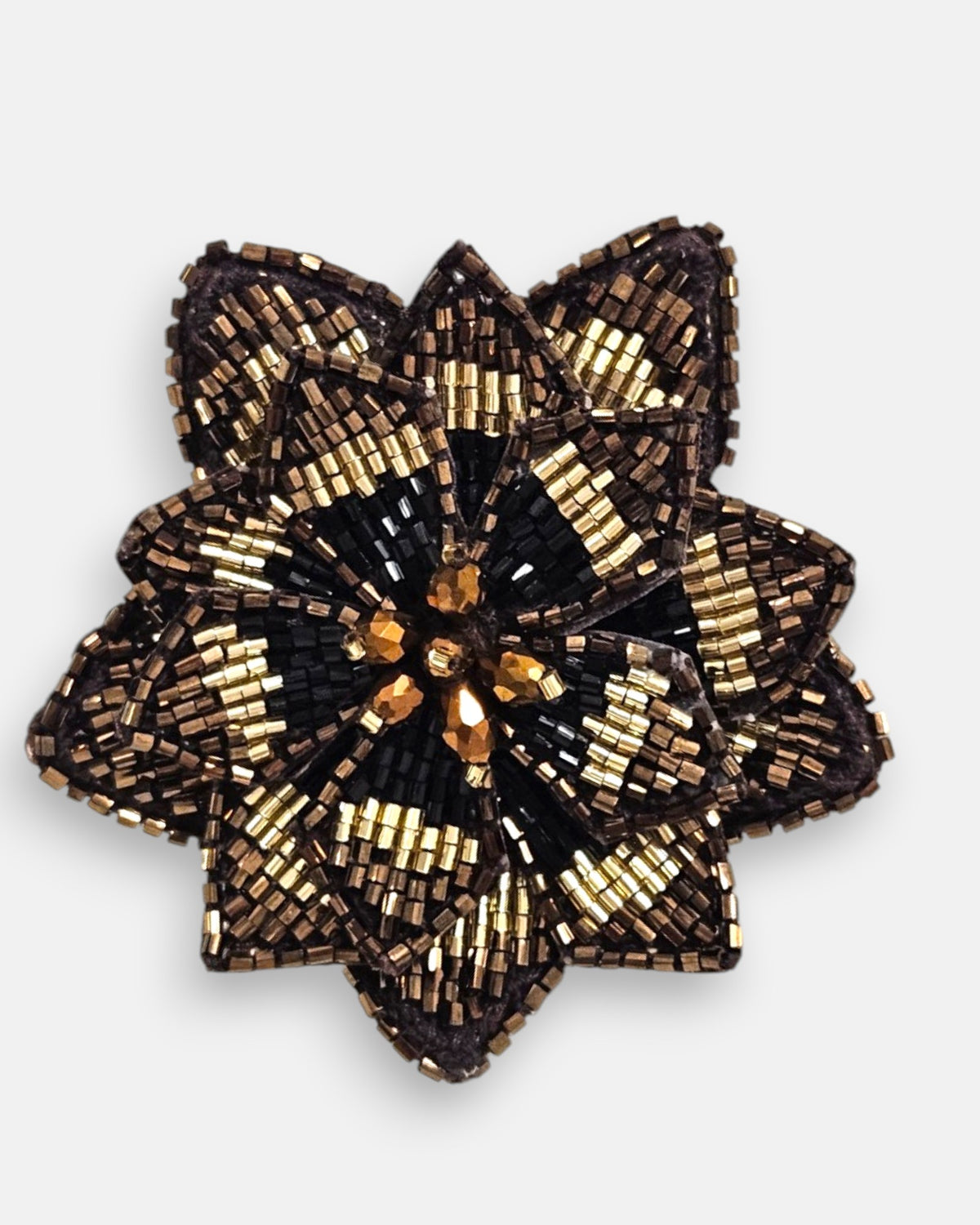 primer plano macro del pendiente Fleur de Lotus Noir et Bronze, permitiendo apreciar el trabajo artesanal de las microcuentas negras y doradas con el centro de cristales bronce.