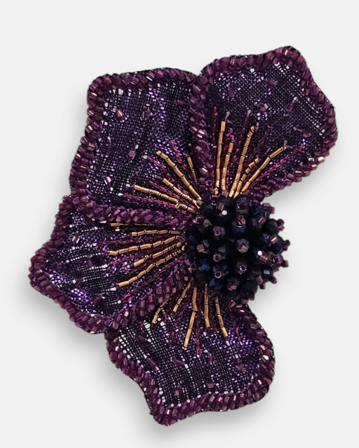 primer plano macro del pendiente Fleur Violette, permitiendo apreciar el tramado de la malla morada, las microcuentas y los pistilos tridimensionales.