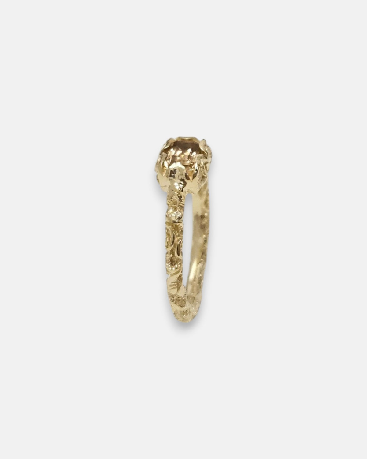 lateral del anillo Nereo, detallando la elevación del engaste esculpido en oro y el aro grabado.