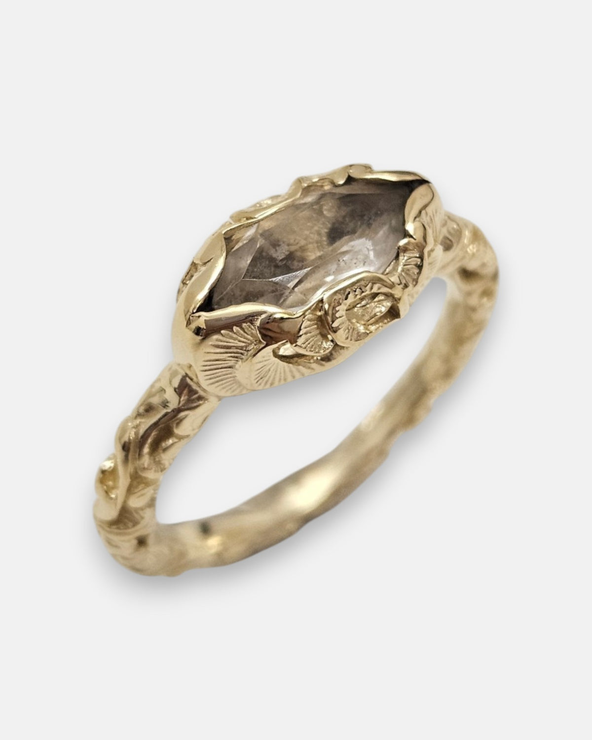 primer plano macro del anillo Beatrice, permitiendo apreciar el cincelado artesanal del cáliz chapado en oro y las facetas del cristal ahumado.