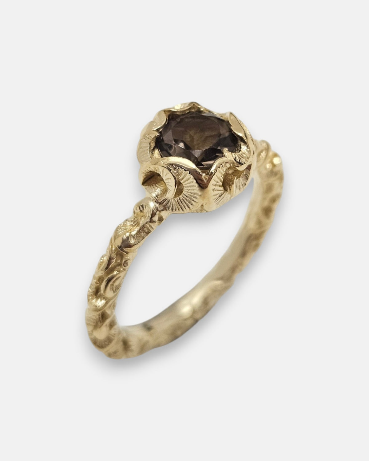 primer plano macro del anillo Celeste, permitiendo apreciar el cincelado artesanal de la flor chapada en oro y las facetas del cristal ahumado.