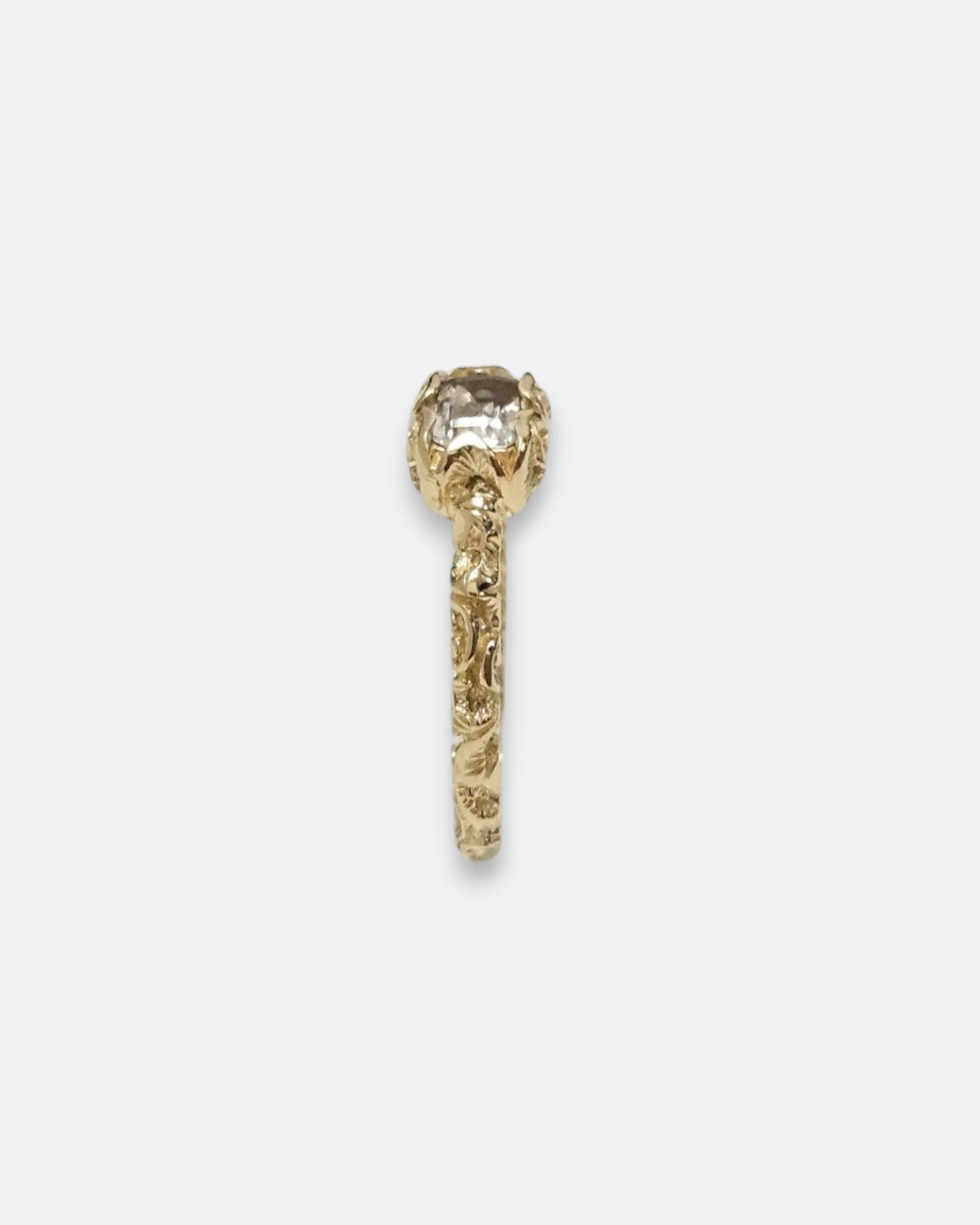 lateral del anillo Zeno, detallando la elevación del engaste esculpido en oro y el aro grabado.