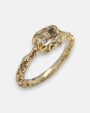 primer plano macro del anillo Zeno, permitiendo apreciar el cincelado artesanal del cáliz chapado en oro y las facetas rectangulares del cristal transparente.