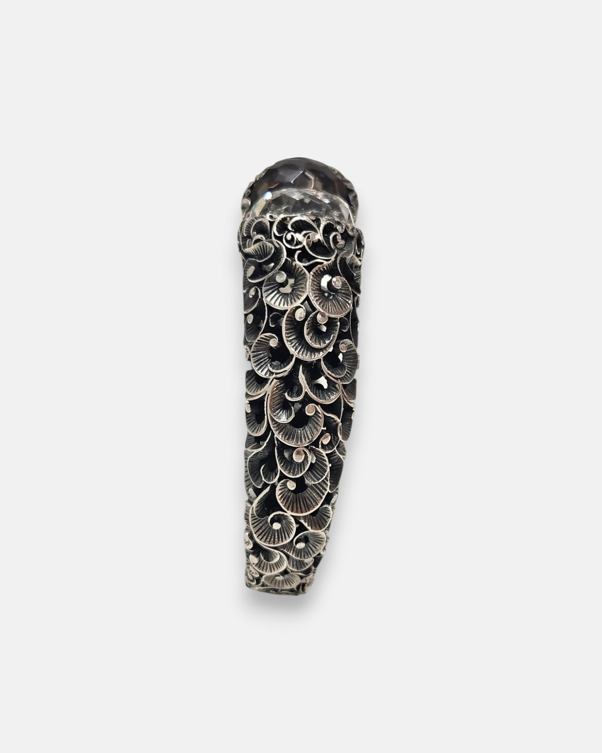 perfil de la pulsera Sibilla, detallando la densidad del labrado artesanal en forma de abanicos y el relieve de la plata bruñida.