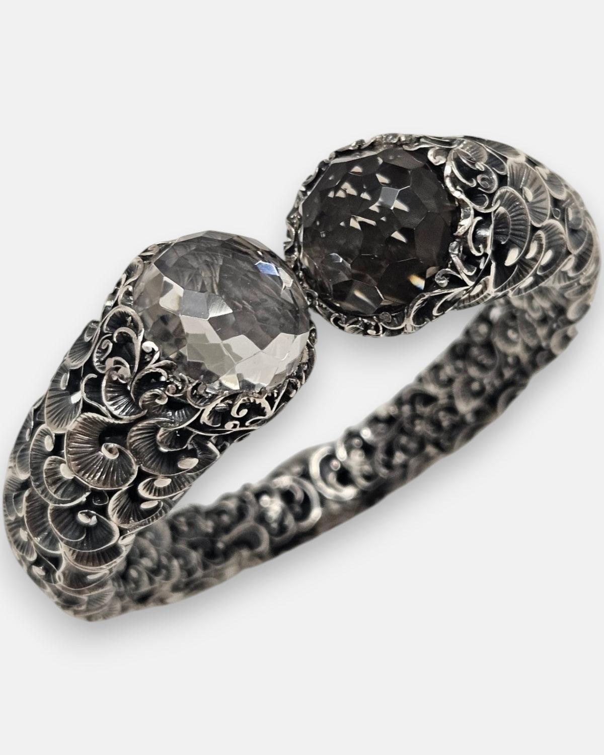 primer plano macro de la pulsera Sibilla, permitiendo apreciar el corte facetado de los cristales transparente y ahumado junto al minucioso cincelado del engaste.