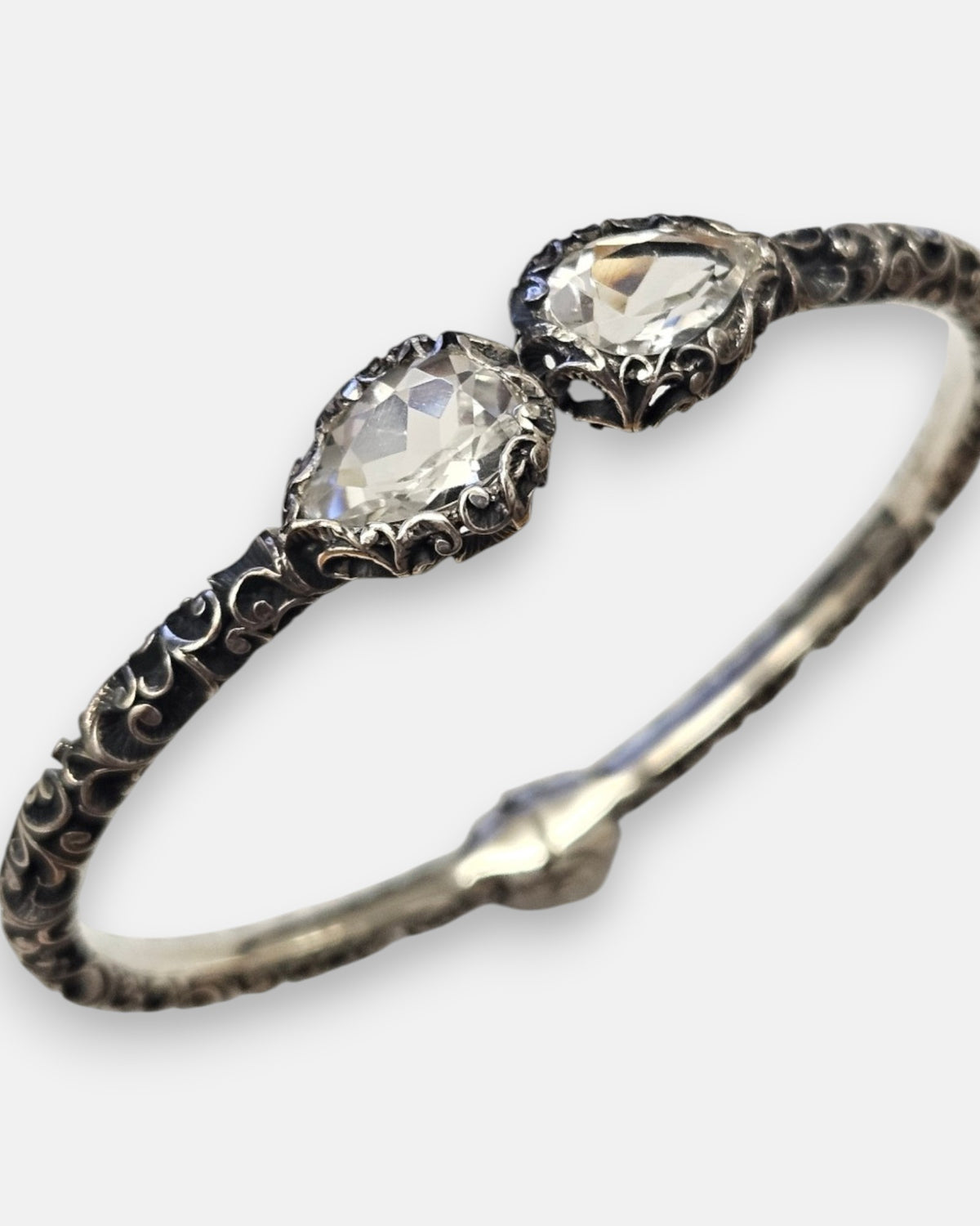 primer plano macro de la pulsera Clarissa, detallando el cincelado artesanal de la plata, la bisagra trasera y el brillo de las gemas en corte pera.