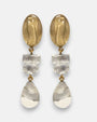 pendientes largos Margot de Dominique Denaive con tres módulos articulados en resina dorada y cristal transparente.