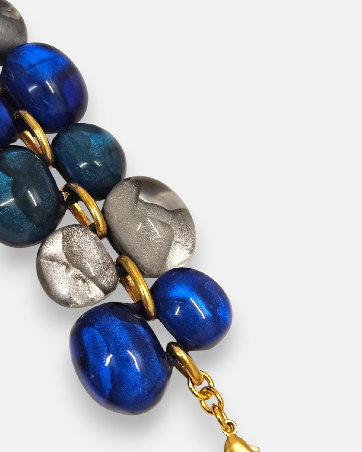 primer plano macro de la pulsera Galet Bleu, permitiendo apreciar el pulido artesanal y los destellos iridiscentes de las cuentas azules y plata.