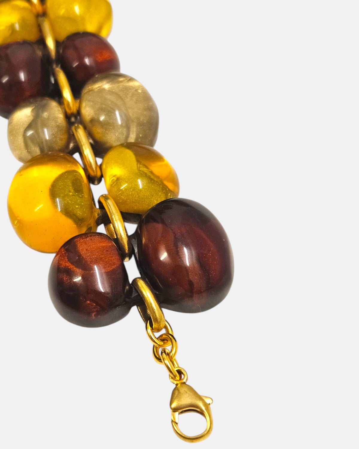 primer plano macro de la pulsera Galet Ambre, permitiendo apreciar el acabado iridiscente de la resina miel y el cierre de mosquetón dorado.