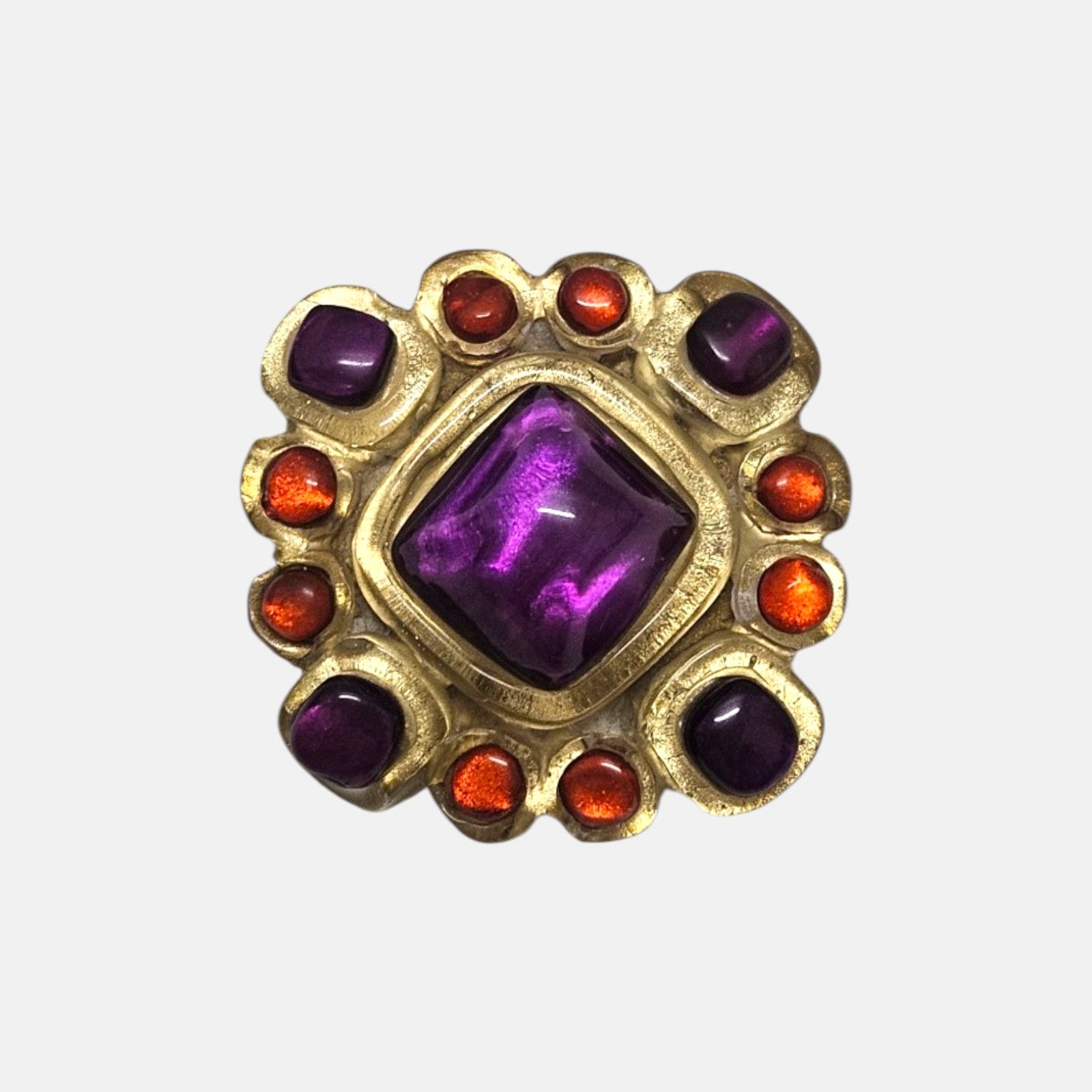 broche de 5x5 cm de Dominique Denaive en resina artesanal dorada con cabujón romboidal violeta y detalles naranjas.