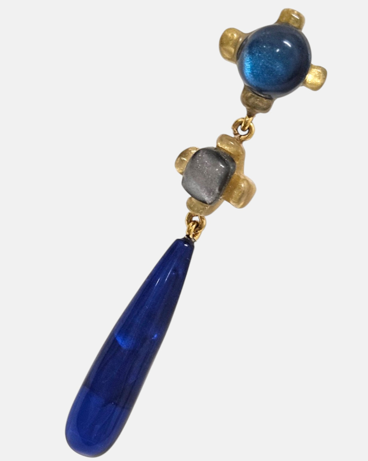 primer plano macro del pendiente Inès Bleu Caída, permitiendo apreciar los matices iridiscentes de la resina azul cobalto y las garras doradas de la montura.