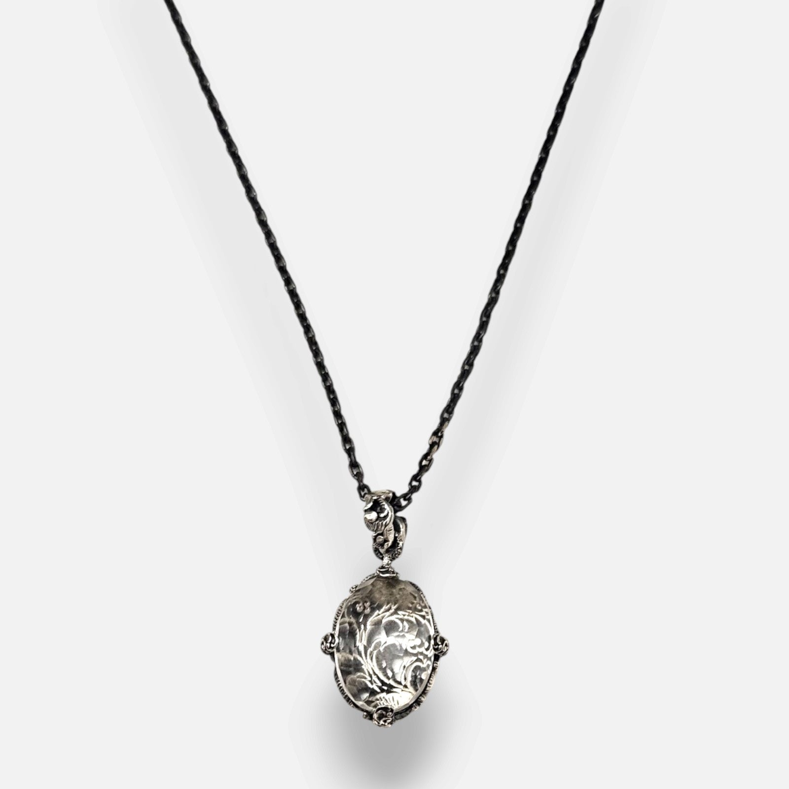 primer plano macro del colgante Médaillon Transparent et Argent Baroque de Maria e Luisa, permitiendo apreciar la talla faceteada del cristal, la reasa ornamentada y las garras de plata envejecida.