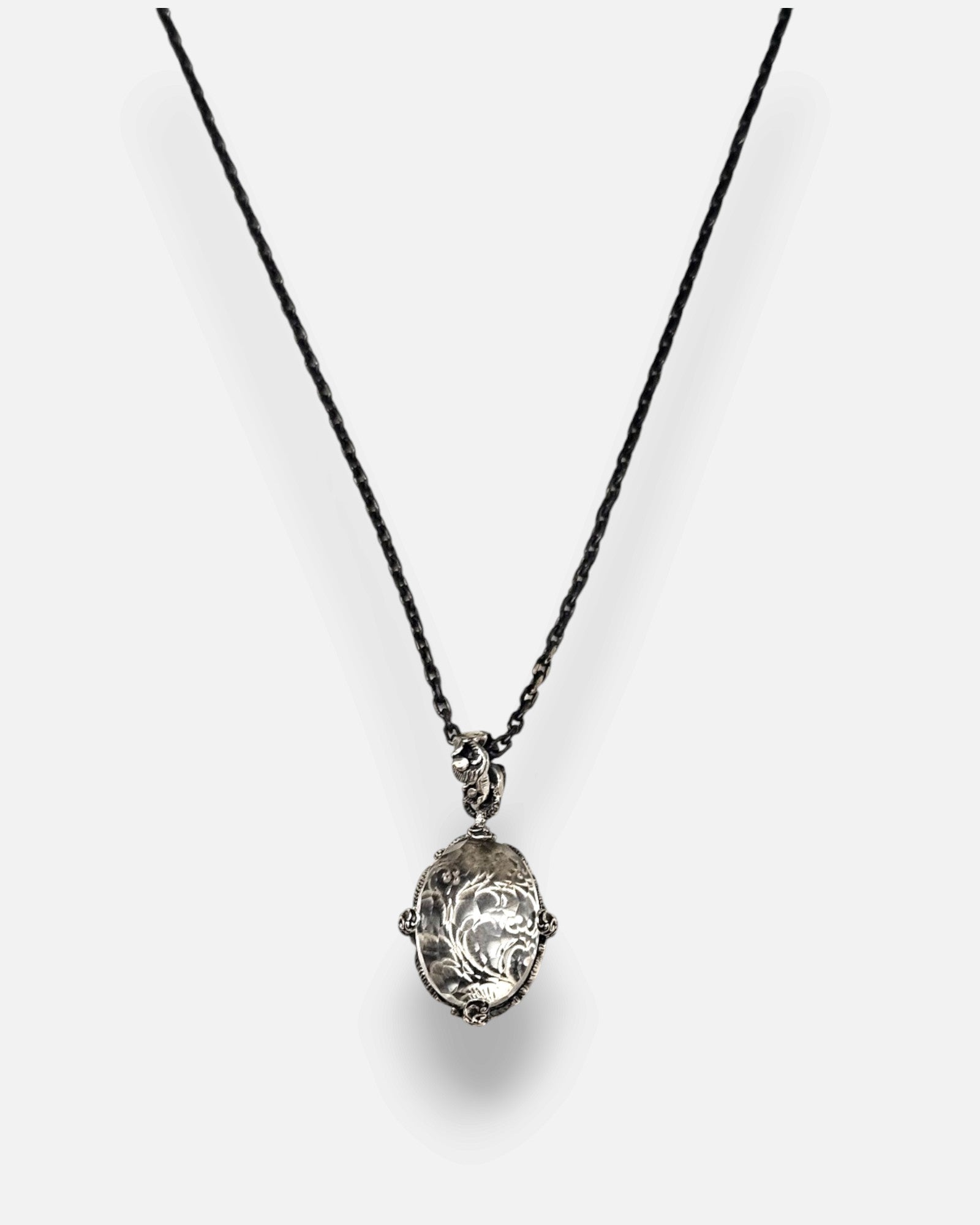 primer plano macro del colgante Médaillon Transparent et Argent Baroque de Maria e Luisa, permitiendo apreciar la talla faceteada del cristal, la reasa ornamentada y las garras de plata envejecida.
