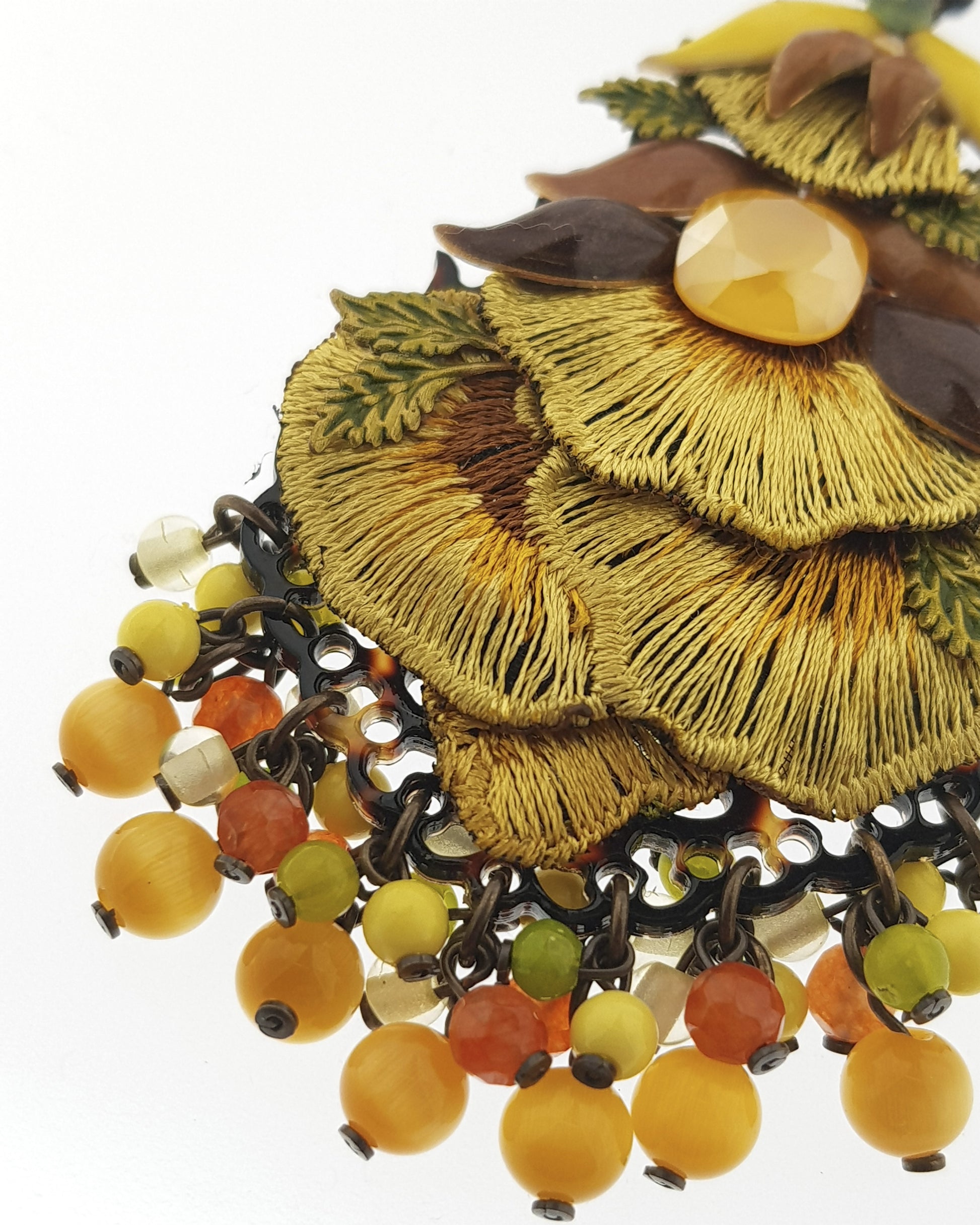 Primer plano del bordado artesanal y el esmaltado de los pendientes Dublos, resaltando la textura y las cuentas de ágata.