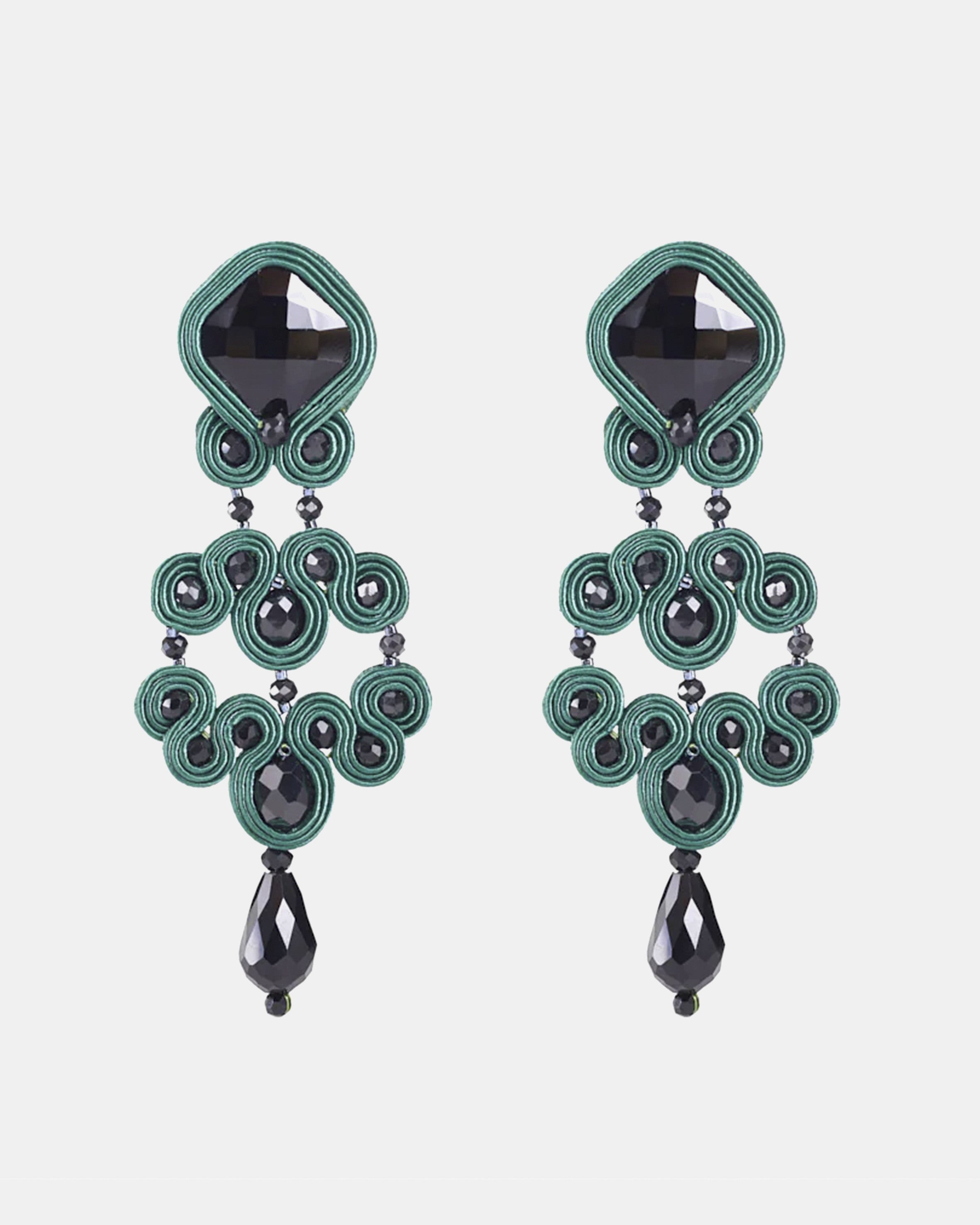 Pareja de pendientes largos Gótico Azabache Verde  con diseño de soutache y cristales negros sobre fondo blanco.