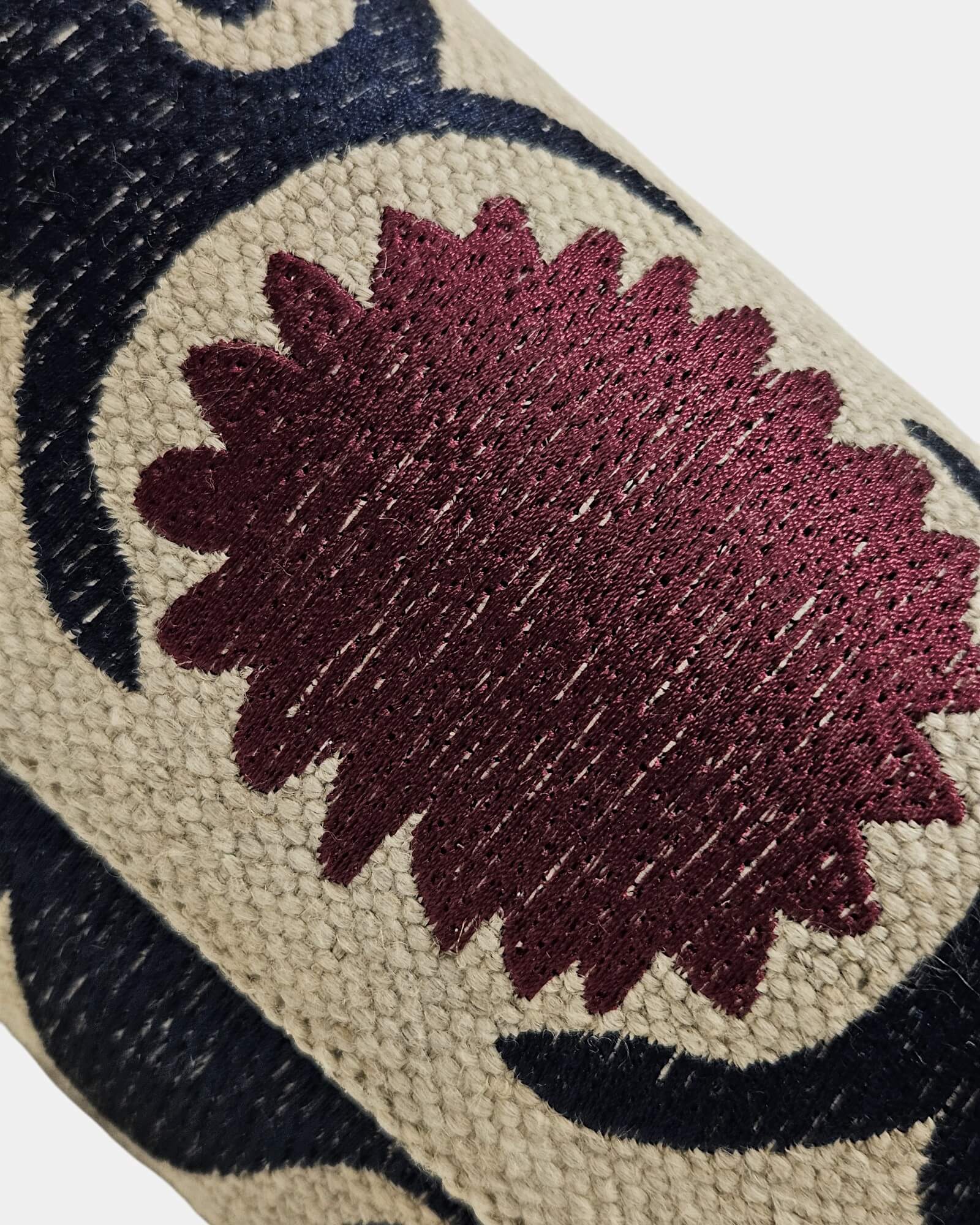 Primer plano de la textura de rafia natural y esquinera metálica decorativa con grabados clásicos y una pequeña piedra roja incrustada.