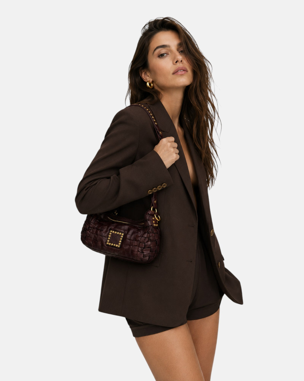 modelo luciendo el bolso trenzado burdeos colgado al hombro, apreciando su escala compacta, su silueta curva y su elegancia casual.