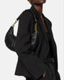 modelo luciendo el bolso Carlotta colgado al hombro sobre una americana negra, apreciando su silueta curva y estilo sofisticado.