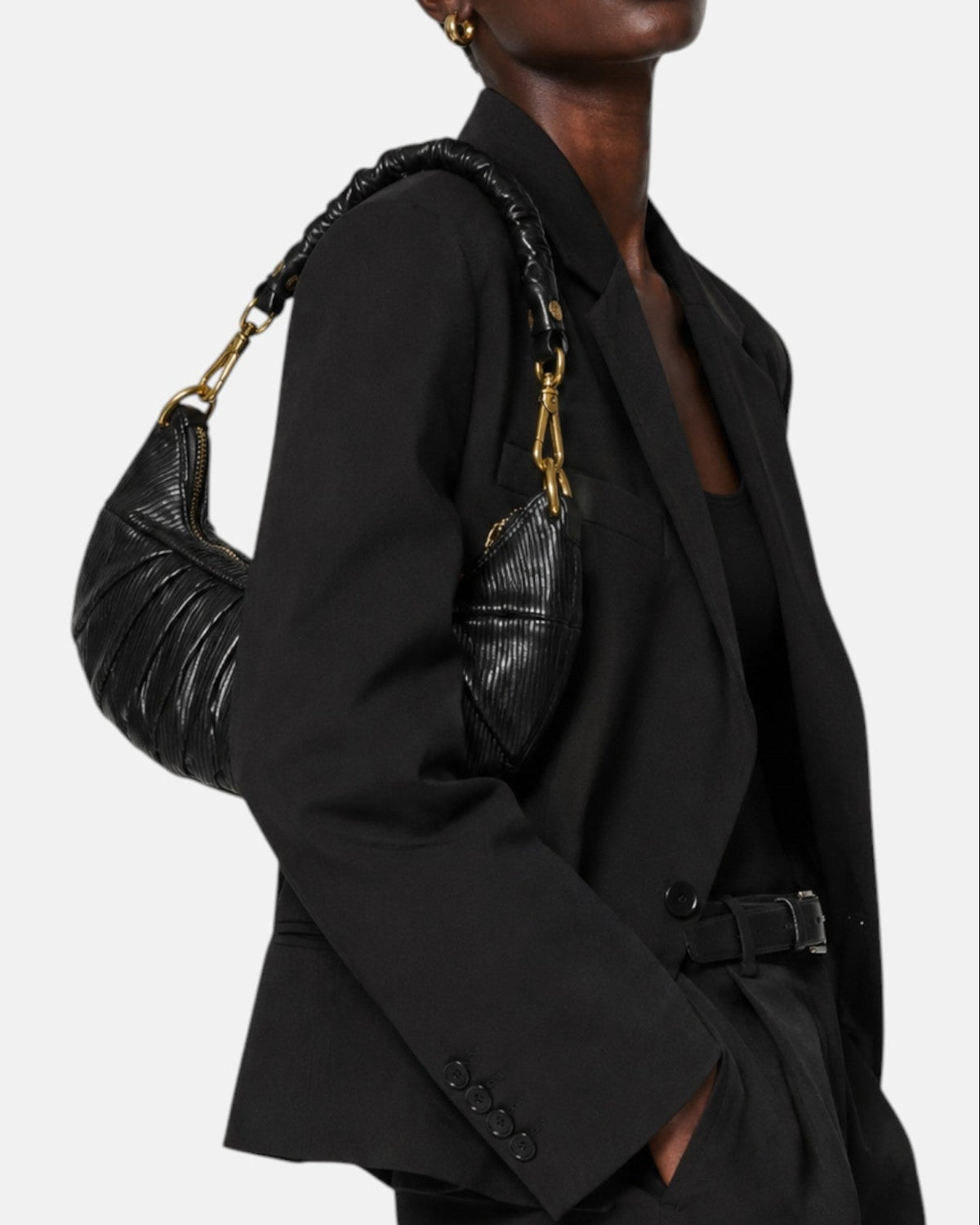 modelo luciendo el bolso Carlotta colgado al hombro sobre una americana negra, apreciando su silueta curva y estilo sofisticado.