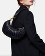 modelo luciendo el bolso Donatella colgado al hombro sobre una americana oscura, apreciando su silueta curva y estilo sofisticado.