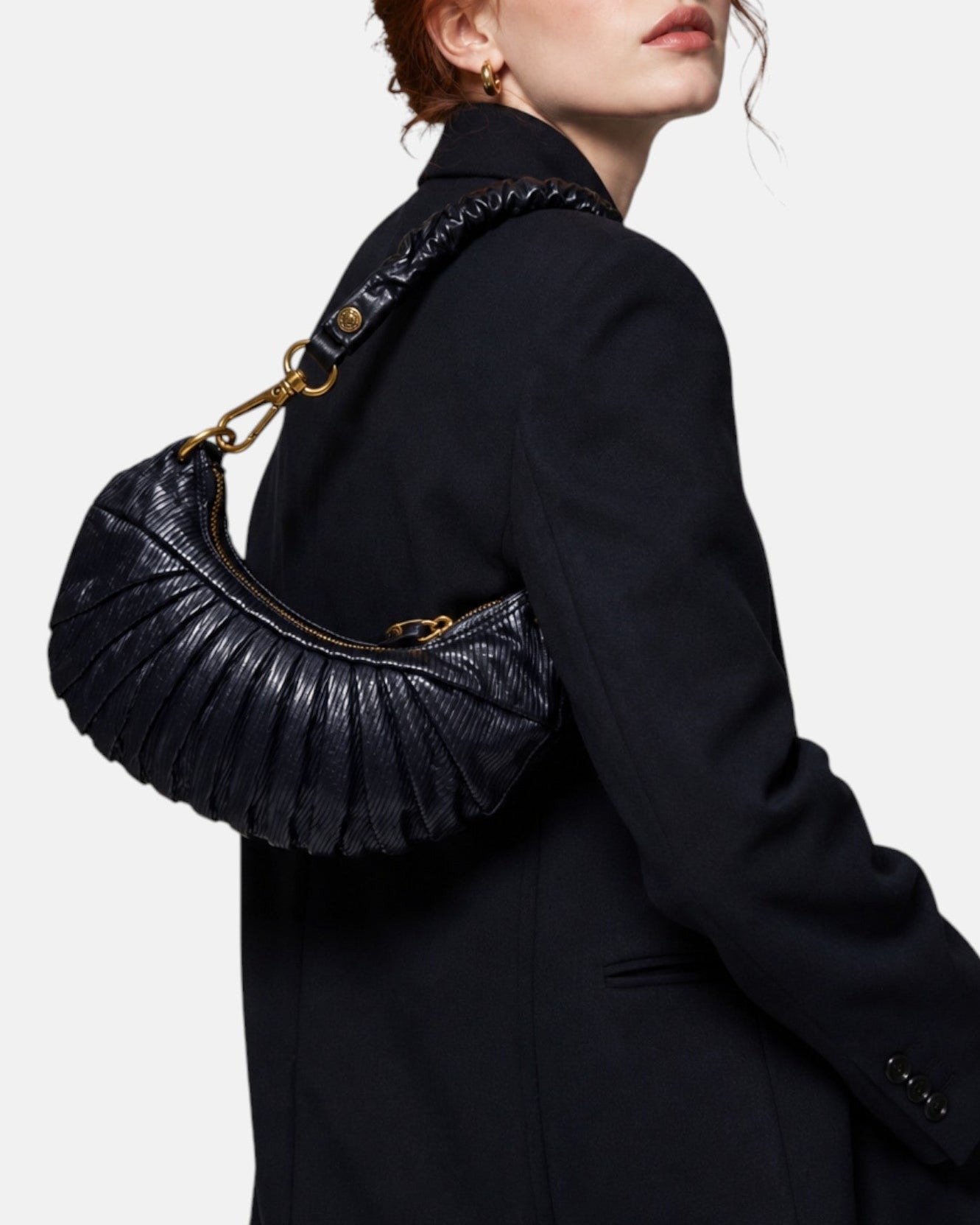 modelo luciendo el bolso Donatella colgado al hombro sobre una americana oscura, apreciando su silueta curva y estilo sofisticado.