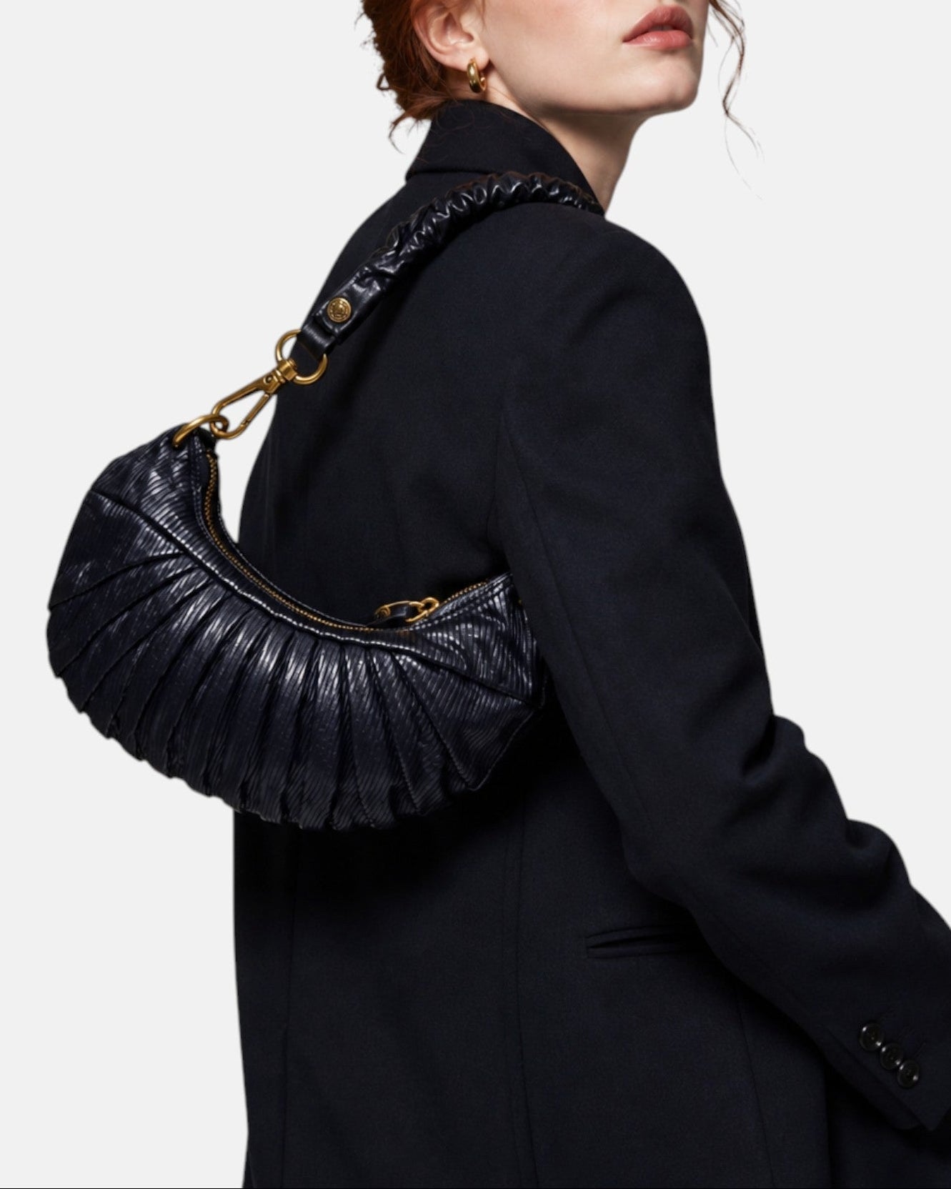 modelo luciendo el bolso Donatella colgado al hombro sobre una americana oscura, apreciando su silueta curva y estilo sofisticado.