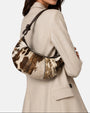 modelo luciendo el bolso Elena colgado al hombro sobre una americana beige, apreciando su escala cómoda y su textura silvestre.