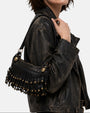 modelo luciendo el bolso Neha colgado al hombro junto a una chaqueta de cuero, apreciando su tamaño compacto y su estilo bohemio.