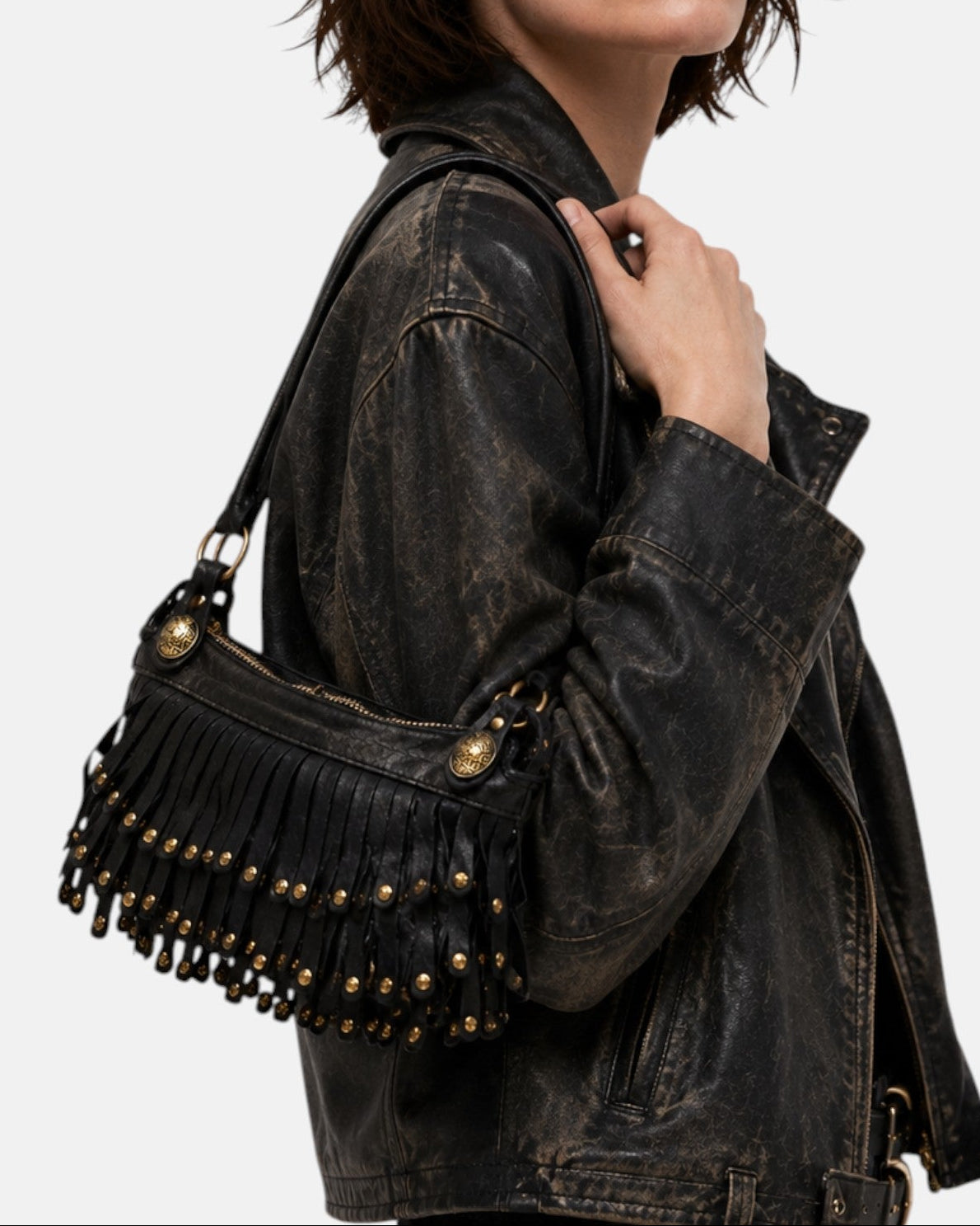 modelo luciendo el bolso Neha colgado al hombro junto a una chaqueta de cuero, apreciando su tamaño compacto y su estilo bohemio.